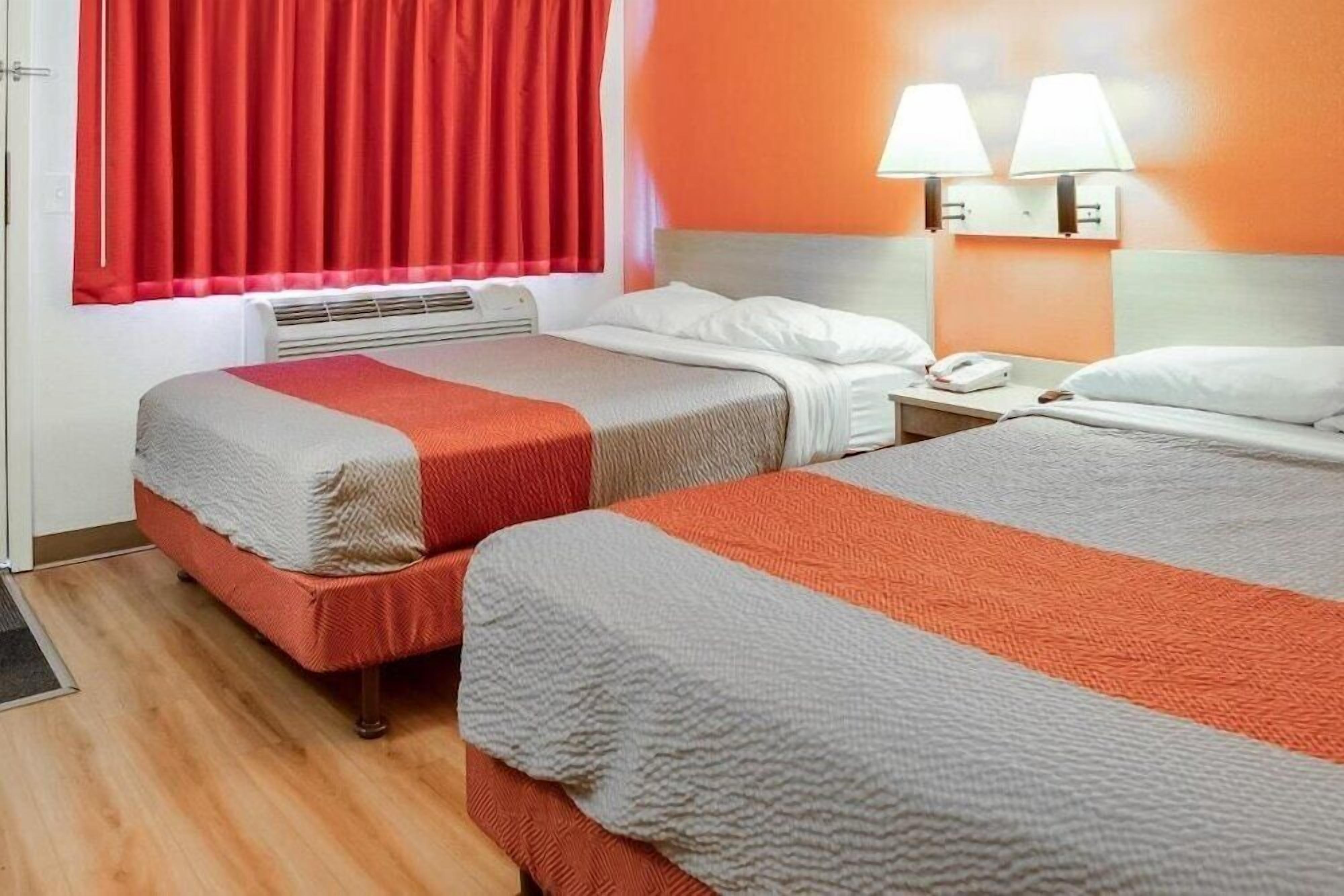 Een hotelkamer met twee bedden, een verwarming, een telefoon en twee wandlampen.