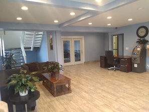 A spacious lobby with a staircase, a reception desk, an ATM, and a seating area with a coffee table and plants. - Sioux City Inn (Sioux City)
