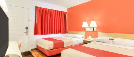 A hotel room with two beds, a desk, a mirror, and a red curtain.