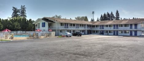 A motel with multiple rooms, a parking lot, and a pool area.