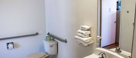 A bathroom with a toilet, a sink, a mirror, and a towel rack.