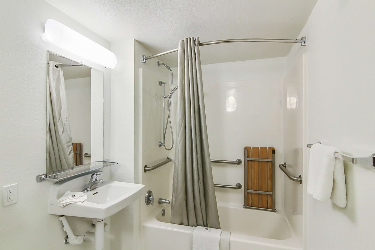 A bathroom with a white sink, mirror, and bathtub.