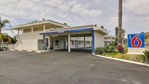 Un motel con un letrero que dice 'welcome', un área de estacionamiento techada y un letrero con el número '6' indicando la cantidad de habitaciones.