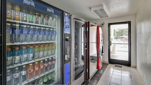 Máquina expendedora llena de diversas bebidas, incluyendo agua Aquafina y otras opciones.