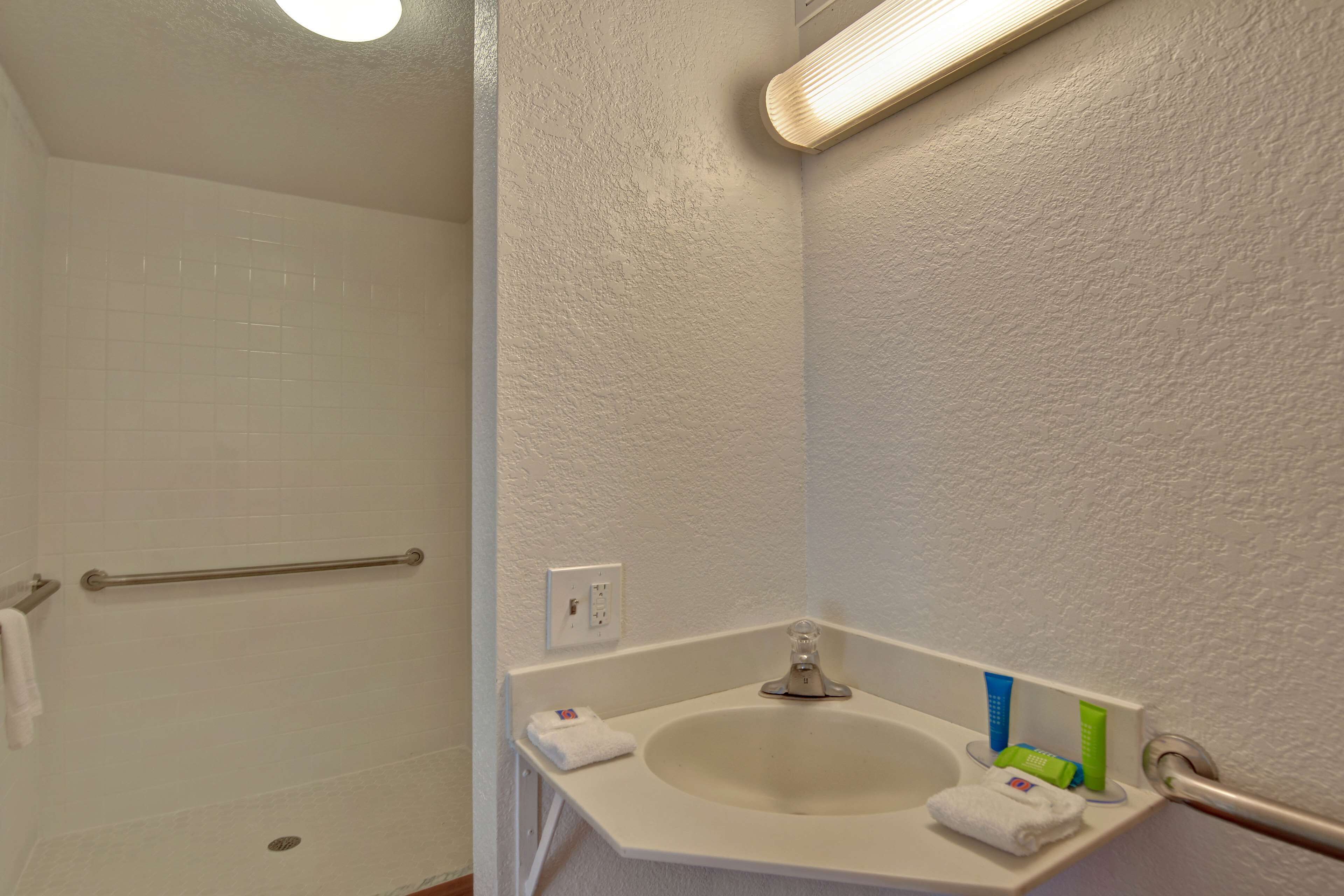 A bathroom with a white sink, a towel rack, and a shower area.