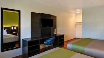 Una habitación de hotel con cama, escritorio, silla, televisor y espejo.