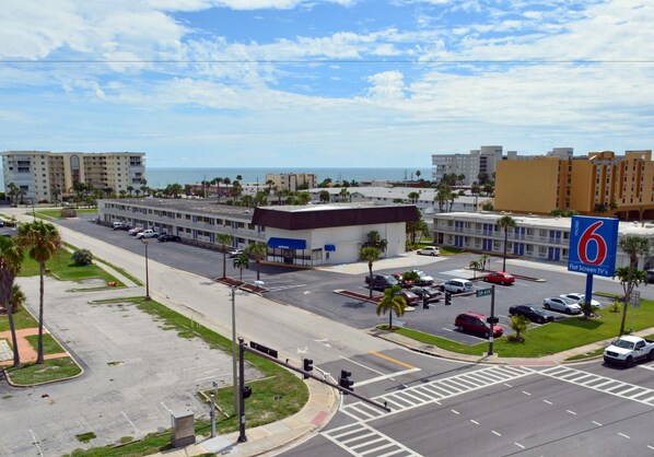 Un hotel con estacionamiento, una intersección de calles y vista al océano.