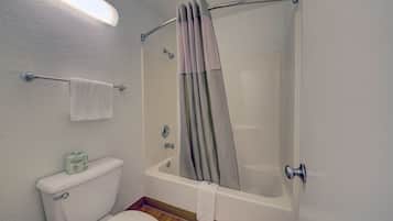 Un baño con inodoro, bañera y cortina de ducha.