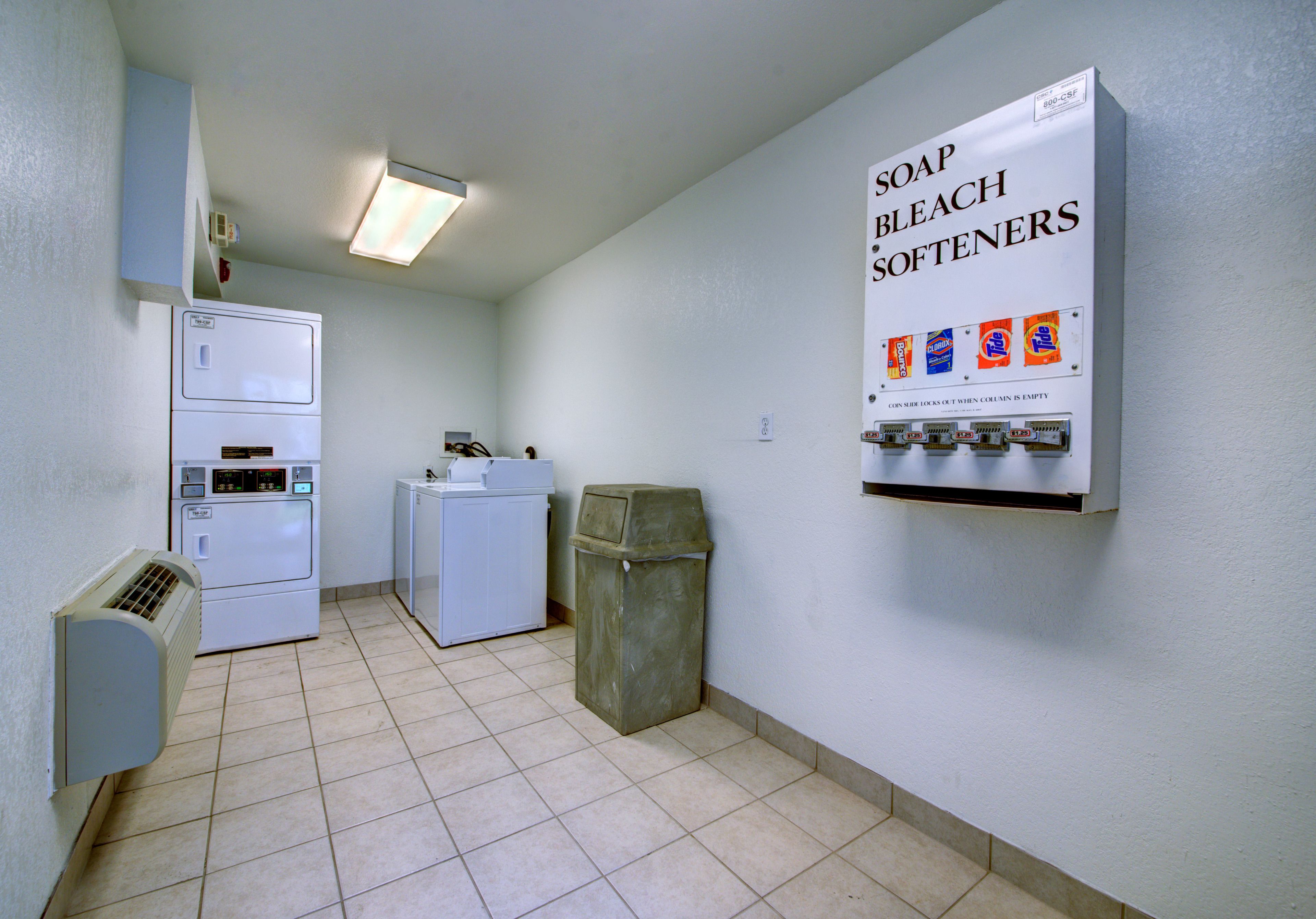 A laundry room with a washing machine, dryer, and a wall-mounted soap dispenser.