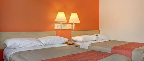 A hotel room with two beds, a nightstand, and a wall-mounted lamp.