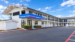 A motel with a 'WELCOME' sign, a covered parking area, and a clear sky. - Motel 6 Amarillo, TX - West (Amarillo)