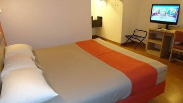Una habitación de hotel con una cama, un televisor y un escritorio con una silla.