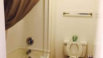 A small bathroom with a bathtub, toilet, and a towel rack.