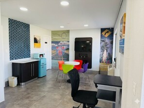 Un espace d’accueil avec un comptoir, un téléviseur et des chaises colorées.