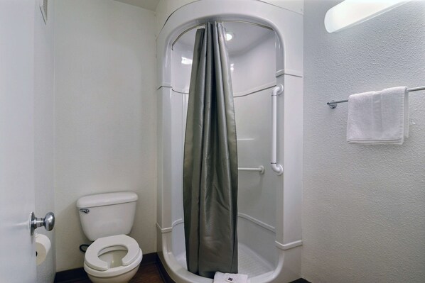 A bathroom with a shower enclosure, toilet, and towel rack.