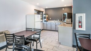 A modern kitchen with a dining area, featuring a refrigerator, microwave, and built-in oven. - Americas Best Value Inn East Peoria (East Peoria)