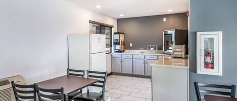 A modern kitchen with a dining area, featuring a refrigerator, microwave, and built-in oven.