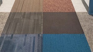 A hotel corridor with a checkered carpet, doors on both sides, and a red emergency light on the right wall. - Americas Best Value Inn East Peoria (East Peoria)