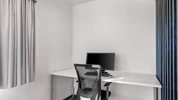 Un espacio de oficina moderno con un escritorio blanco, una silla de oficina de malla negra, un monitor de computadora y un teclado.
