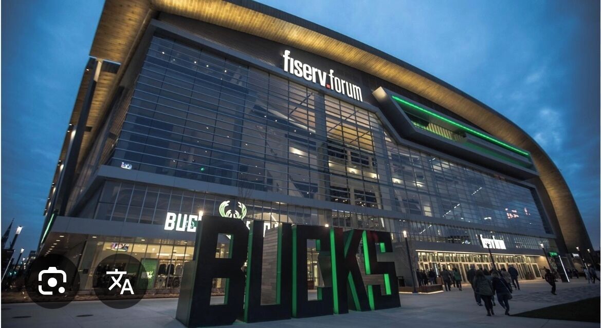 A modern building with large glass windows and a prominent 'fiserv. forum' sign.
