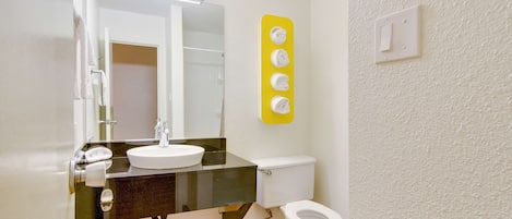 Une salle de bain avec un lavabo blanc, un miroir et des toilettes.