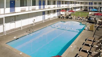 A motel with a swimming pool, multiple balconies, and outdoor seating.