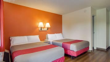 Une chambre d’hôtel avec deux lits, une table de chevet et deux lampes fixées au mur.