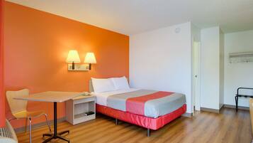 A hotel room with a bed, a desk, and two wall-mounted lamps.
