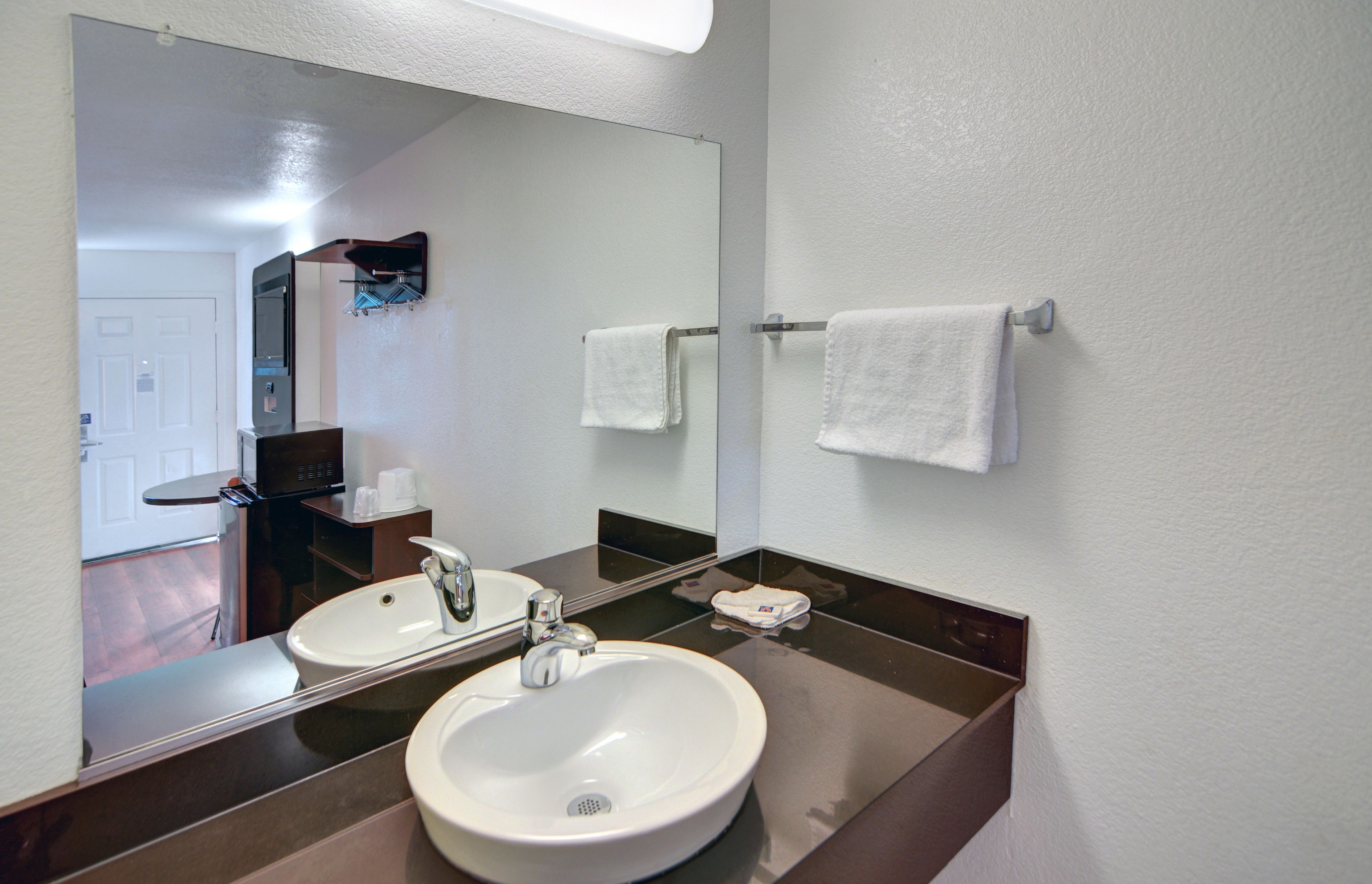 A bathroom with two sinks, a large mirror, and a towel rack.