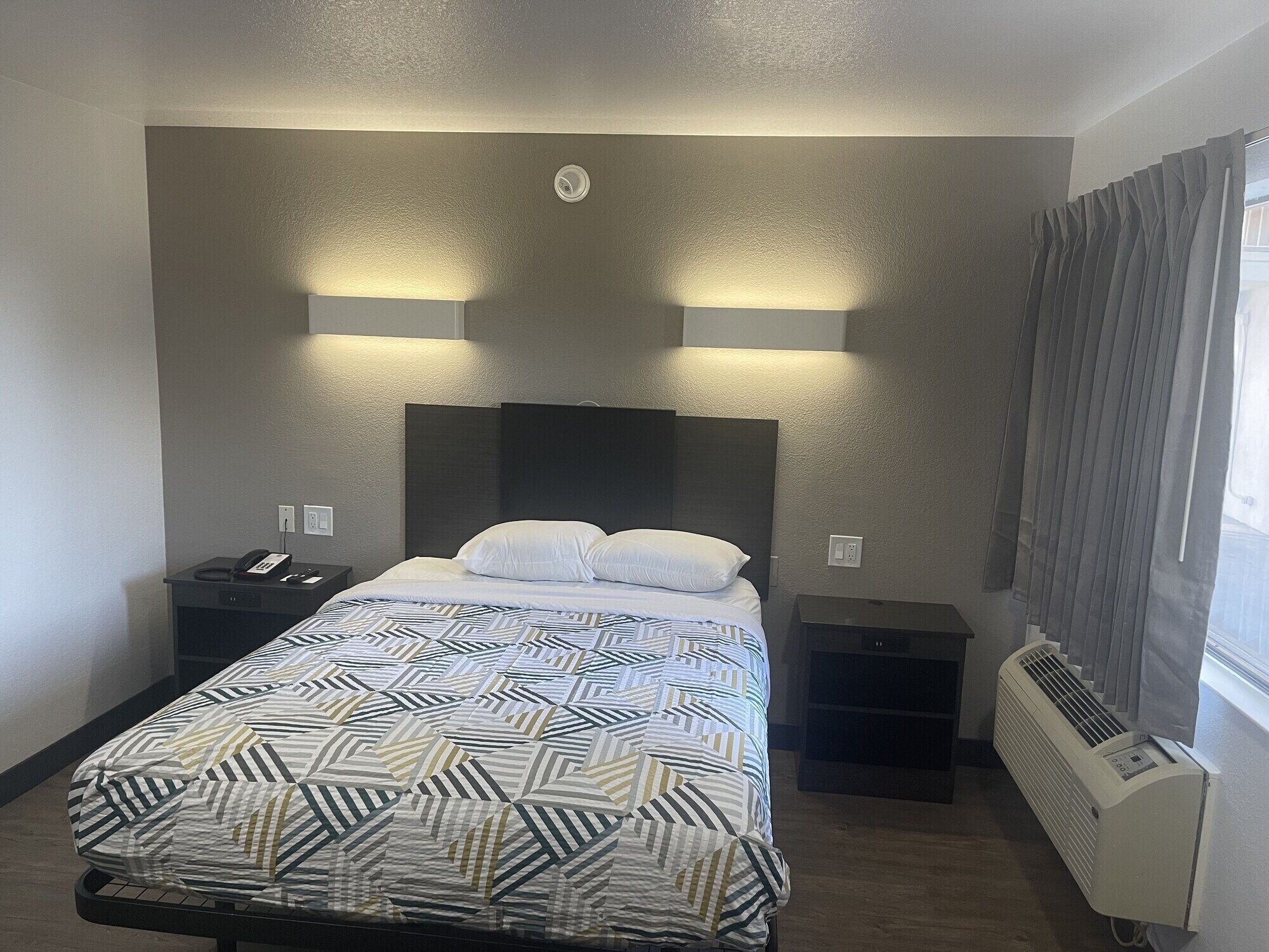 Une chambre d’hôtel équipée d’un lit, de tables de chevet, d’un téléphone et d’un radiateur.
