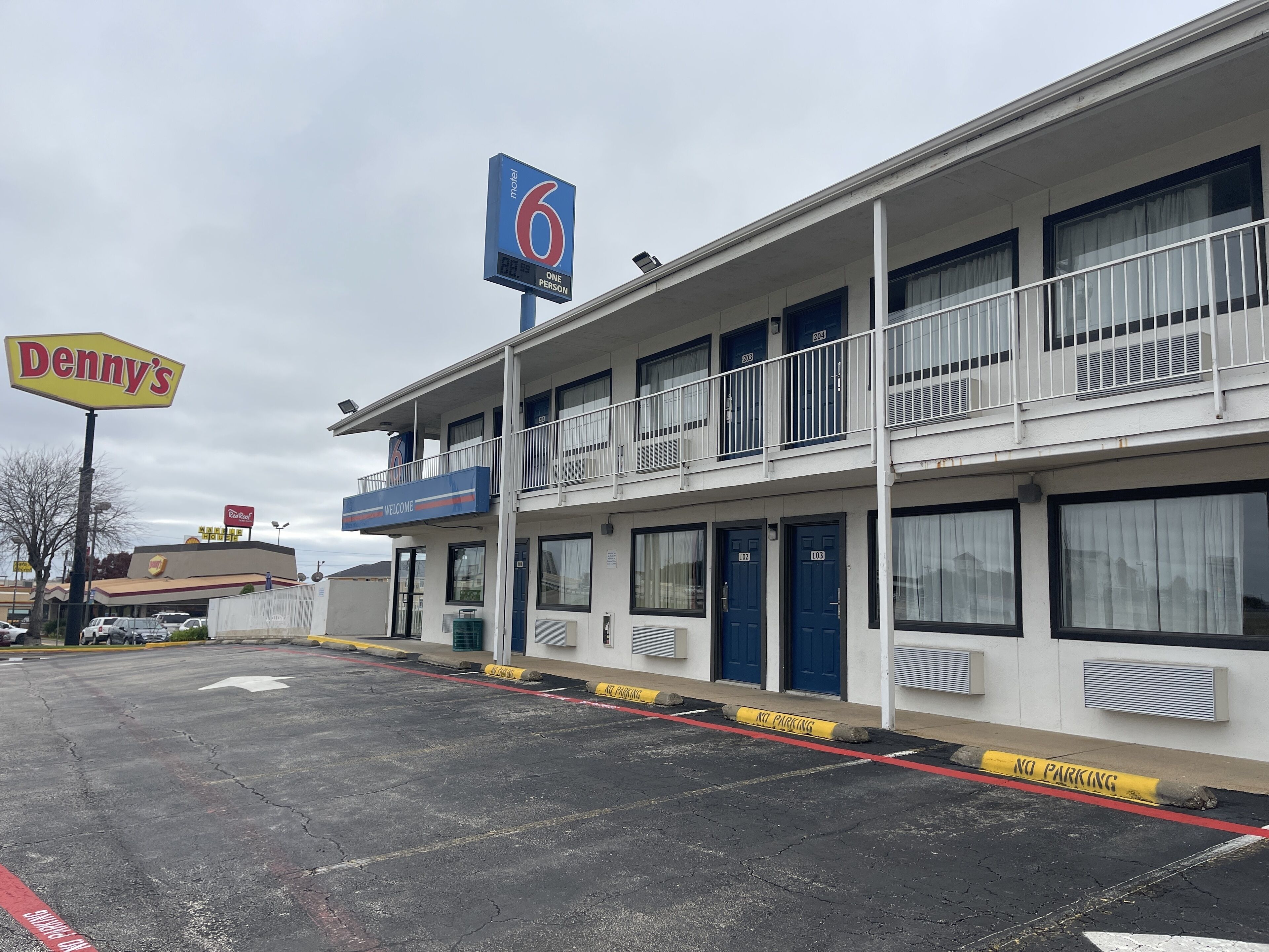 A motel with a '6' sign, a 'Welcome' sign, and a 'No Parking' sign.