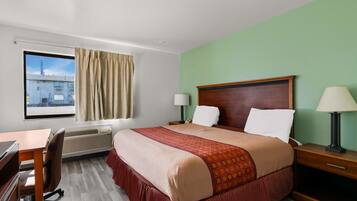 Habitación de hotel con una cama grande, dos mesitas de noche con lámparas, un escritorio con silla, una ventana con cortinas y un equipo de aire acondicionado.