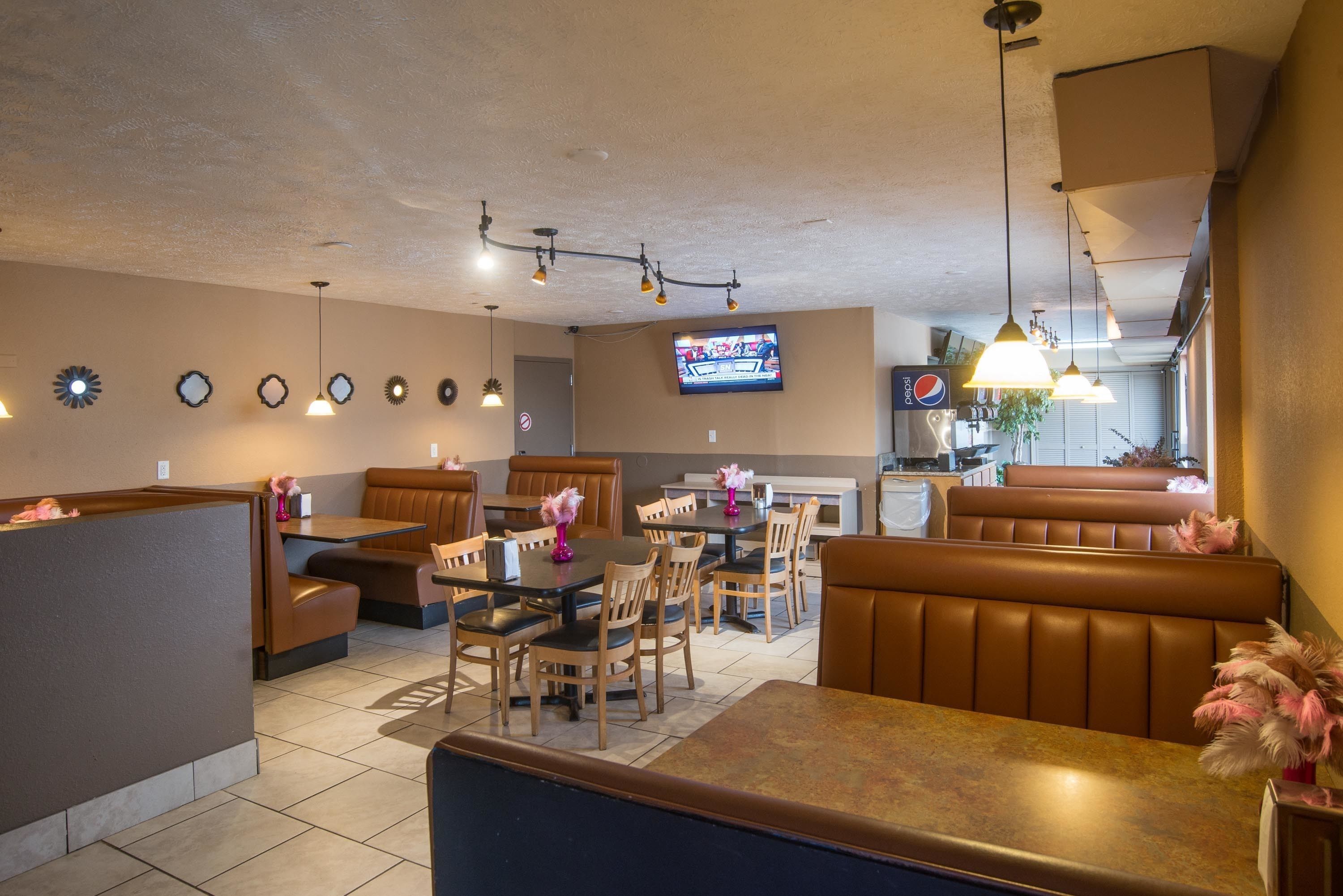A restaurant with booths, tables, and a television screen.