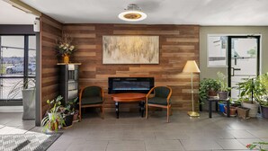 Een modern interieur met een open haard, twee fauteuils, een tafel en verschillende potplanten.
