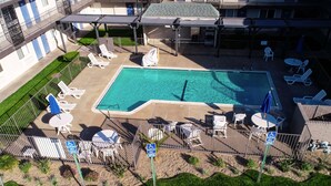 Zona de piscina en la azotea con sillones de descanso, sombrillas y un cartel que indica estacionamiento para huéspedes con discapacidad.