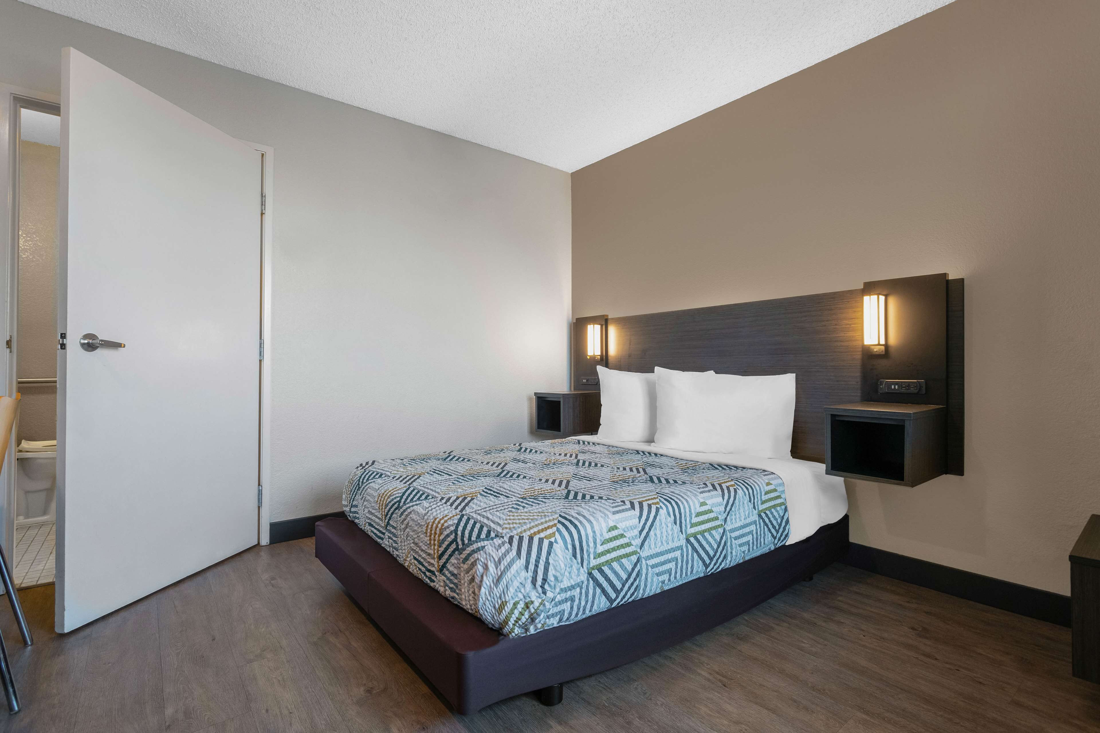 Un dormitorio moderno con una cama grande, dos mesitas de noche y una lámpara de pared.