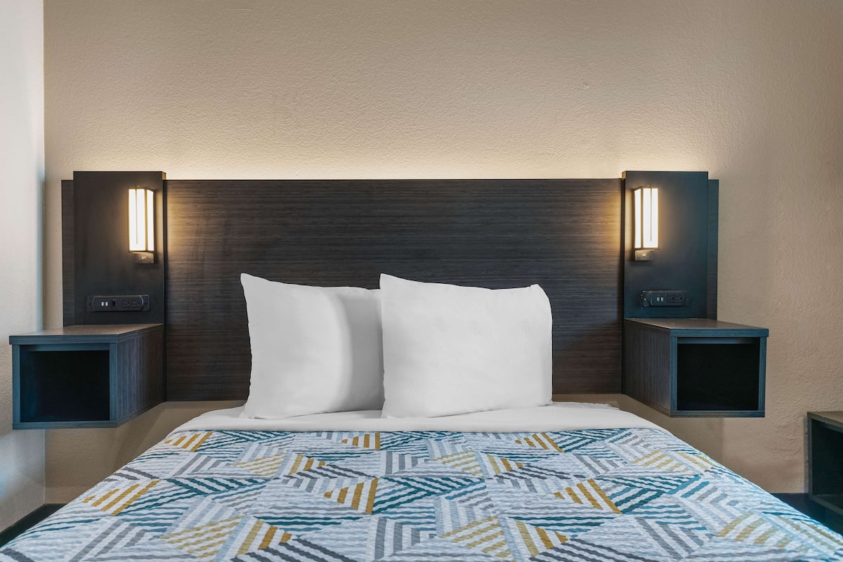 A hotel room with a large bed, two bedside tables, and wall-mounted lighting.