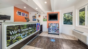 A reception area with a digital display, a TV, and a magazine rack. - Motel 6 Rohnert Park, CA (Rohnert Park)