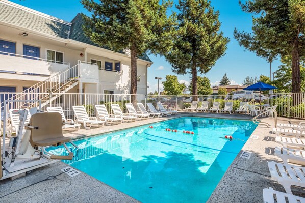 A swimming pool with lounge chairs and a building with multiple doors and windows.