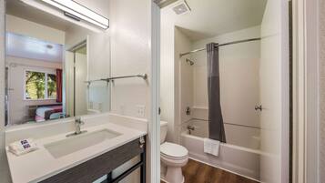 Un bany modern amb un mirall gran, un lavabo, un vàter i una banyera.