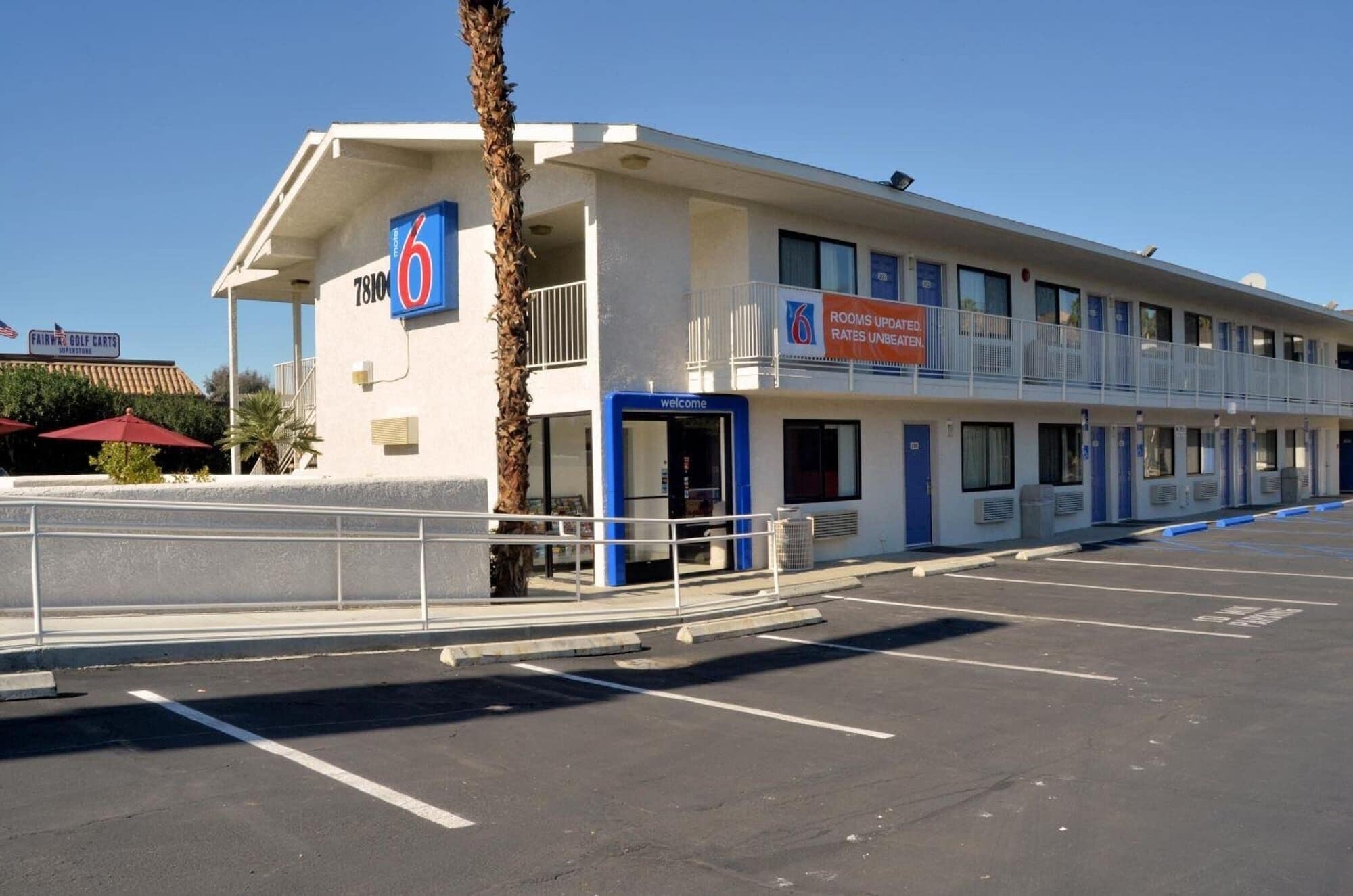 Un motel avec un panneau indiquant le chiffre « 6 », une entrée accueillante et un parking.
