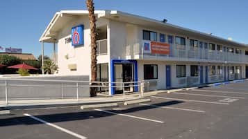 Un motel avec un panneau indiquant le chiffre « 6 », une entrée accueillante et un parking.