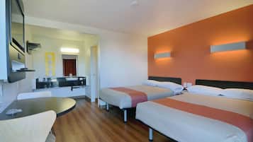 Une chambre d’hôtel avec deux lits, une petite table, une chaise, un lavabo et un miroir.