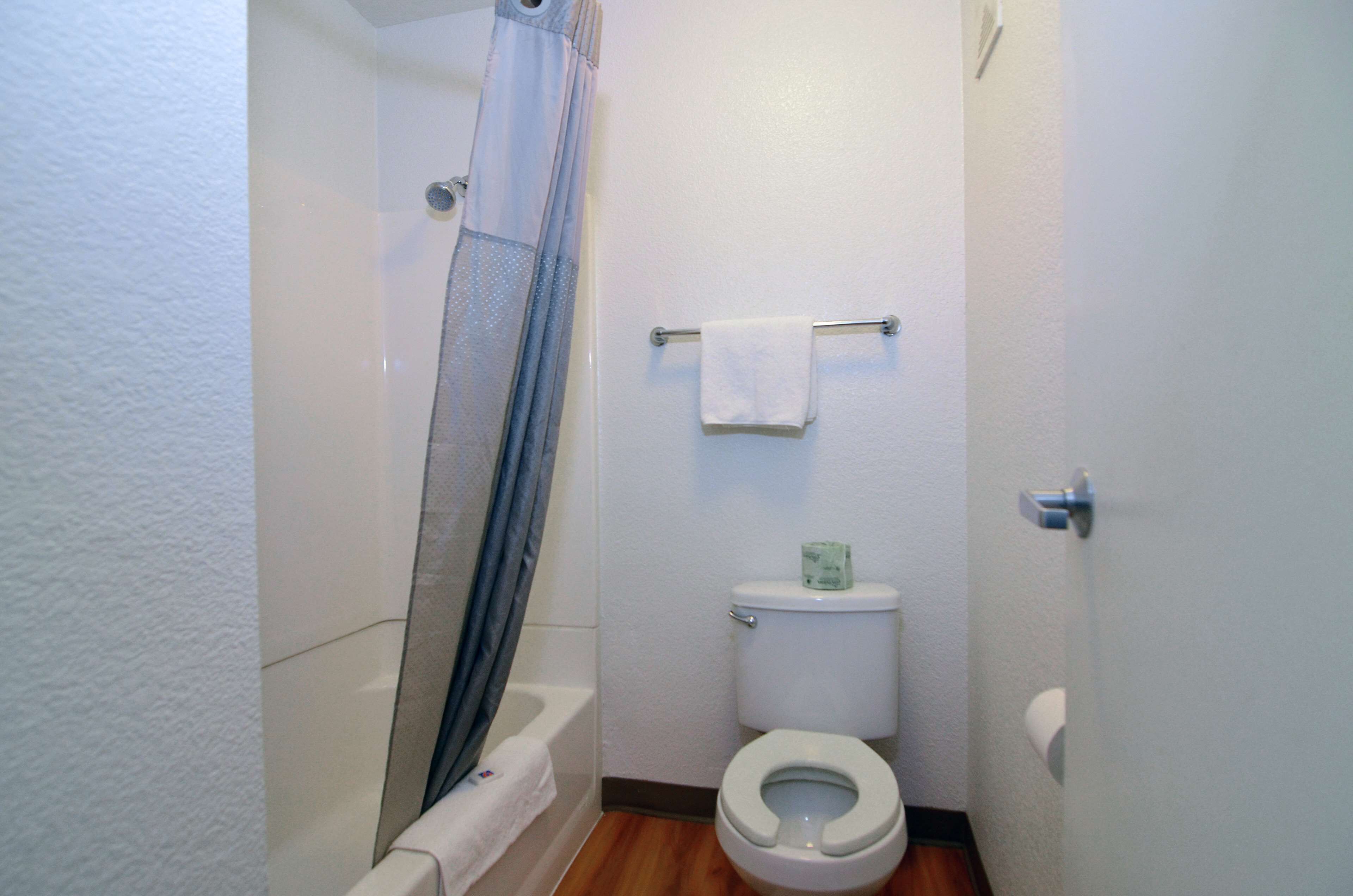 Un baño pequeño con ducha, inodoro y perchero para toallas.