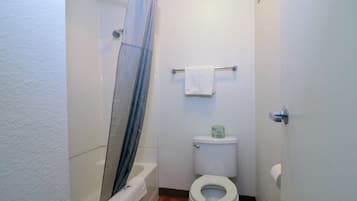 Un baño pequeño con ducha, inodoro y perchero para toallas.