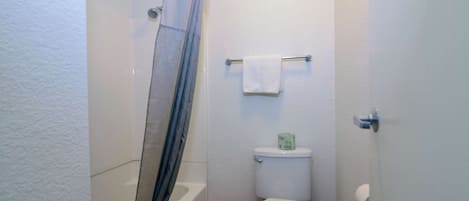 Un baño pequeño con ducha, inodoro y perchero para toallas.