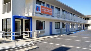 A motel with a blue entrance, a sign indicating rooms are updated, and a parking lot. - Motel 6 Palm Desert, CA - Palm Springs Area (Palm Desert)