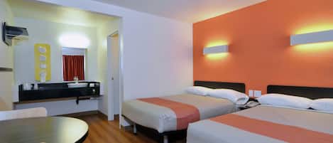 Een hotelkamer met twee eenpersoonsbedden, een klein tafeltje, een wastafel en een spiegel.