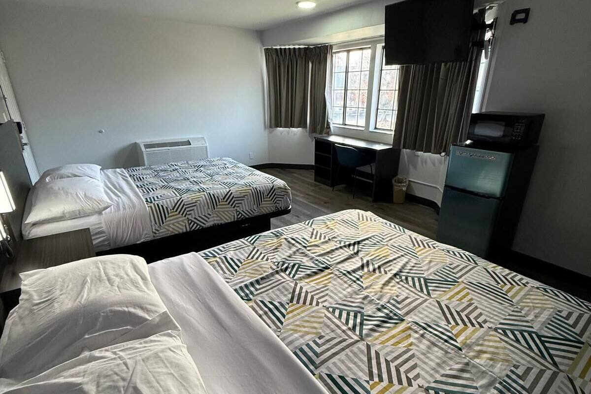 Habitación de hotel con dos camas, un escritorio, un televisor y un microondas.
