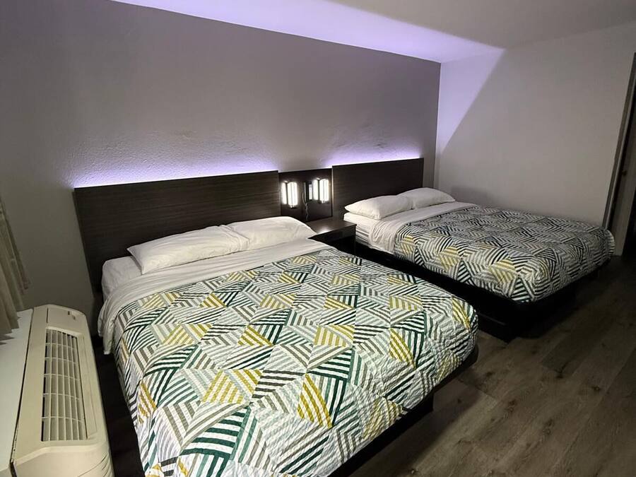 Et hotelværelse med to senge, begge med mønstret sengetøj og senelamper.